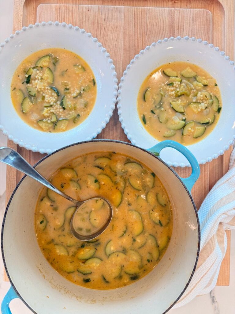 Nonna's Penicillin Soup in a blue Dutch oven with two bowls ready to serve