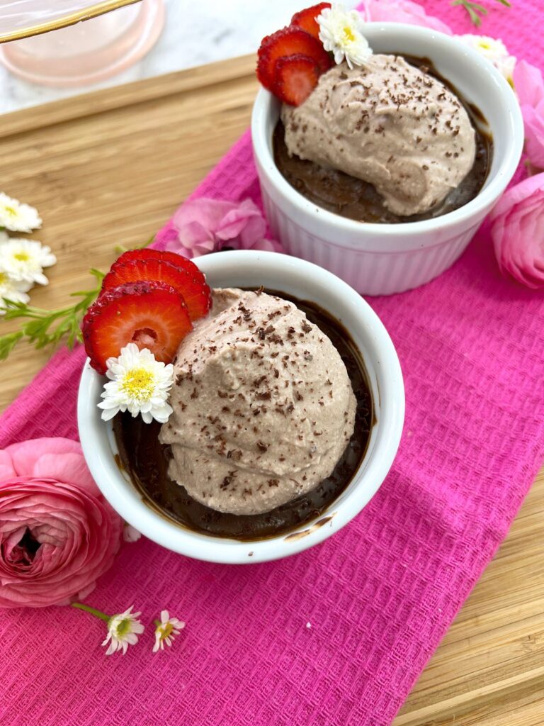 Vegan Chocolate Mousse in white ramekins with whipped cream, grated chocolate, strawberries and daisies